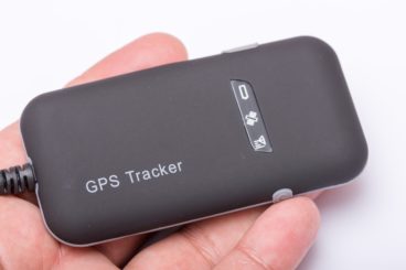 human hand holding a black gps tracker