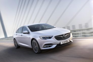 a metallic vauxhall Insignia Grand Sport hatchback driving over bridge with blurred background