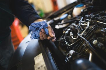 Close up hands of unrecognizable mechanic doing car service and maintenance. Oil and fuel filter changing.