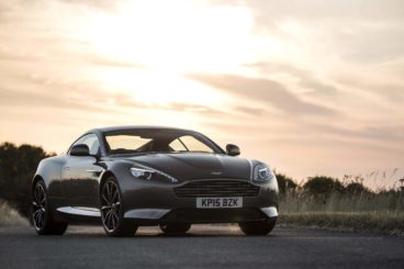 Aston Martin DB9 GT in black parked on a road with the sun setting behind it
