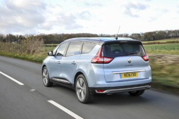 metallic renault grand scenic estate driving on tarmac road with grass at the side