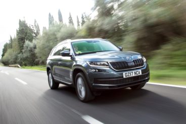 metallic grey skoda kodiaq driving on tarmac road with blurred background