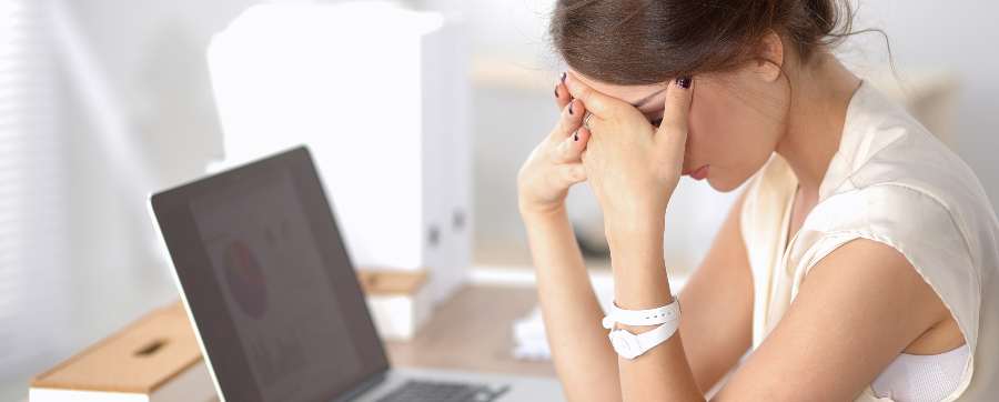 Woman with head in hands in front of computer