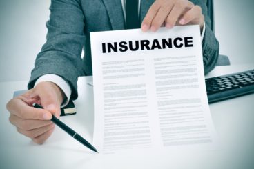 Man holding insurance document with a pen pointing towards it in conjunction to leasing a van