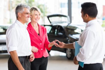senior couple receiving car key after buying a new car