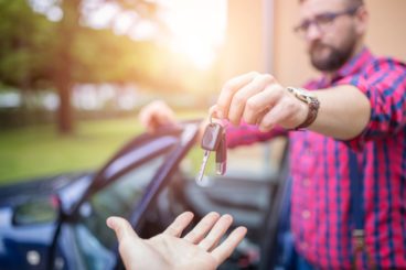 Man standing by the car and giving back car keys