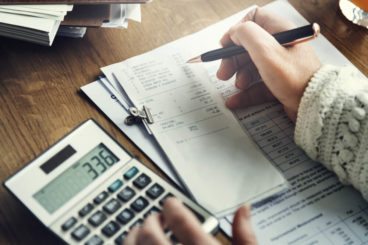 person in a knitted jumper with receipts and a calculator showing 336
