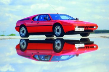 BMW M1 in red parked in a puddle in the sun