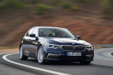 BMW 5 series gran turismo hatchback driving with yellow field in the background