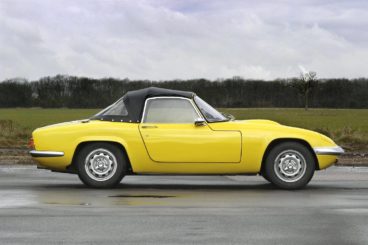 Yellow Lotus Elan parked on a track on a wet road