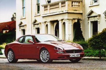 Red Maserati 3200 GT parked outside a manor house