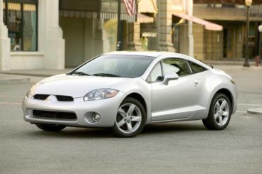 Silver Mitsubishi Eclipse parked on a road with old buildings behind it