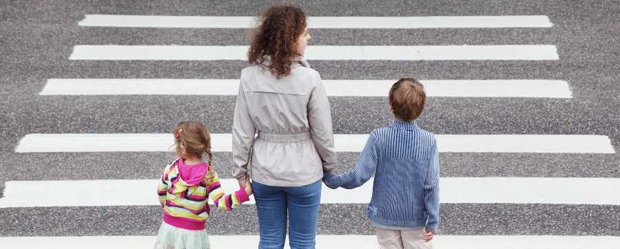 Mother crossing the road with two children at a zebra crossing