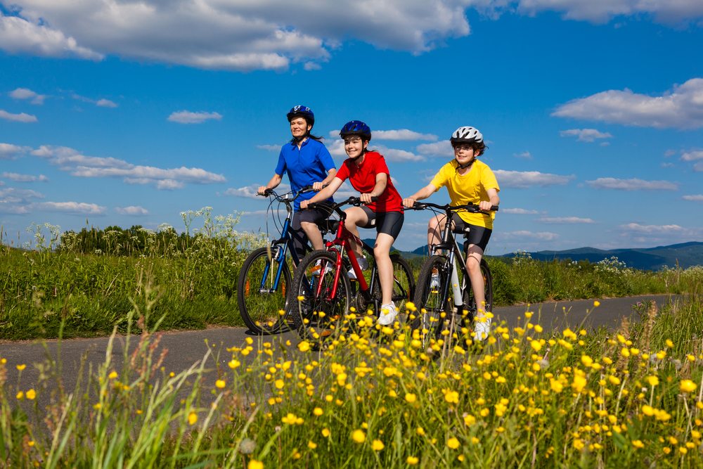 family in brightly coloured clothing cycling along a country road on a sunny day
