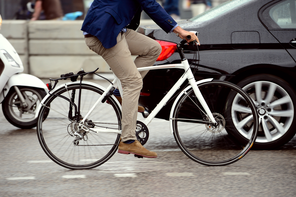 smartly dressed man in blue blazer and chinos with brogues riding a white bike in a city