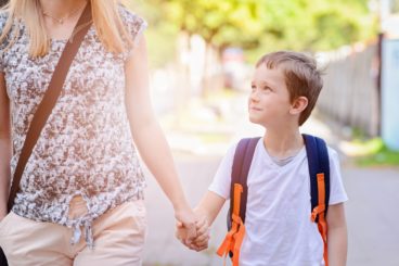 parent holding childs hand whilst crossing the road