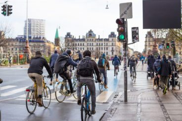 group of cyclists in a city cycling on the road with a green traffic light