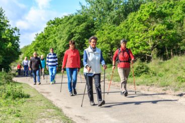 a group of ramblers walking along a country road in the sunshine