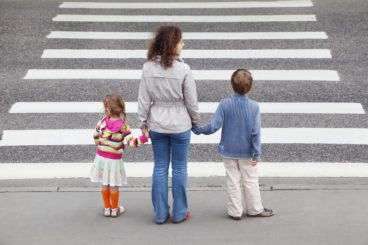 mother with two children waiting to cross at a zebra crossing