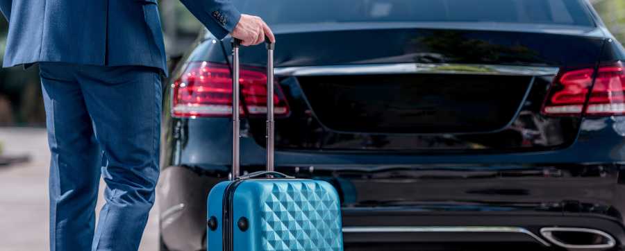 Man with suitcase with open car boot