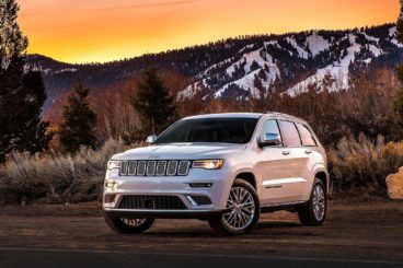 a pearl white jeep grand cherokee in front of snowing mountains and Autumn trees