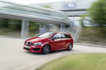 a red mercedes b class diesel hatchback driving round corner with a blurred background