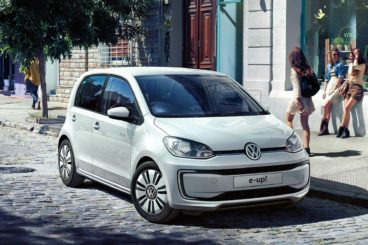 a metallic white volkswagen e-Up! parked in city street