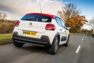a white and red Citroen C3 diesel hatchback driving on tarmac road with autumn trees in the background