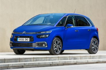 a bright metallic blue Citroen c4 picasso diesel estate parked on pavement in front of wall