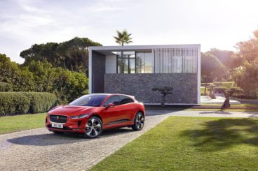a bright red jaguar i pace parked on driveway in front of modern house