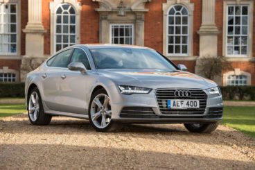 a silver audi a7 parked on sand in front of country house
