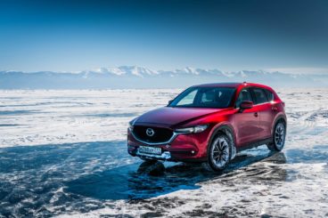 a metallic red mazda cx5 parked on large frozen over lake