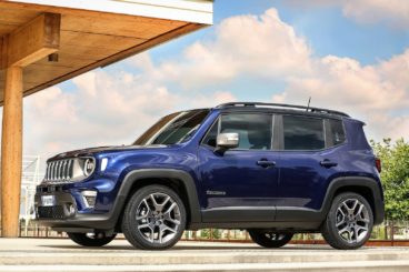 a metallic blue jeep renegade diesel hatchback parked on tarmac with wooden building in the background