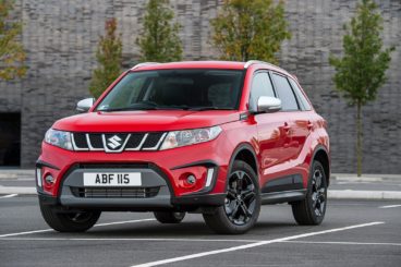 a red Suzuki vitara parked in tarmac parking lot