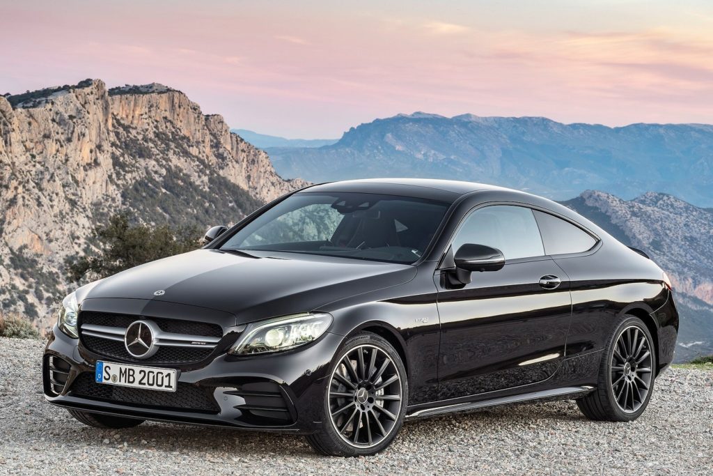 a black mercedes c class coupe on a side of a mountain at sunset