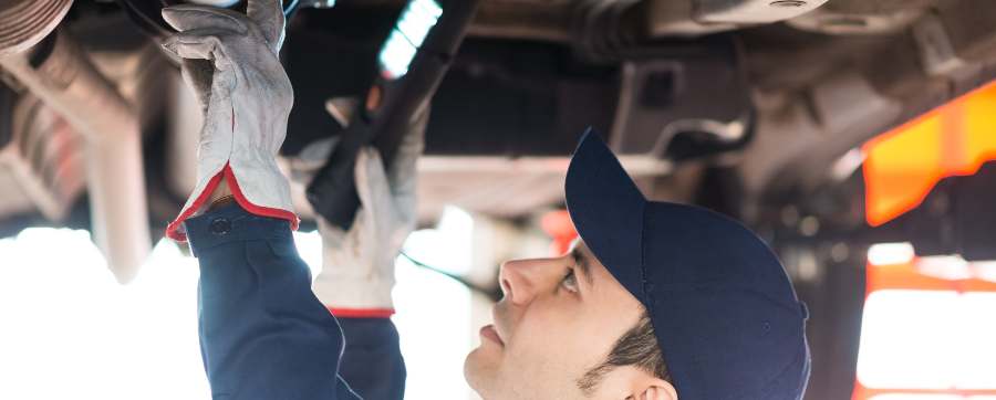 Mercedes service cost - Mechanic examining underside of car