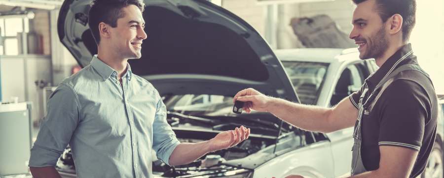 MOT - Mechanic handing car keys back to owner with car in background