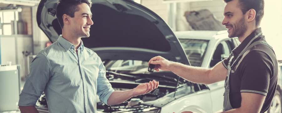 MOT - Mechanic handing car keys back to owner with car in background