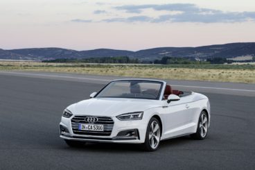 a white audi a5 cabriolet parked on tarmac with mountains in the background at sunset