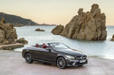 a dark coloured mercedes c class cabriolet parked near cliffs