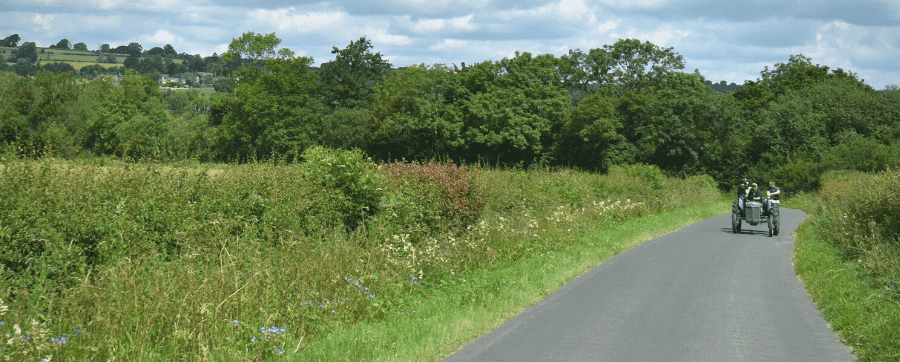 A small tractor driving through a lane in the countryside