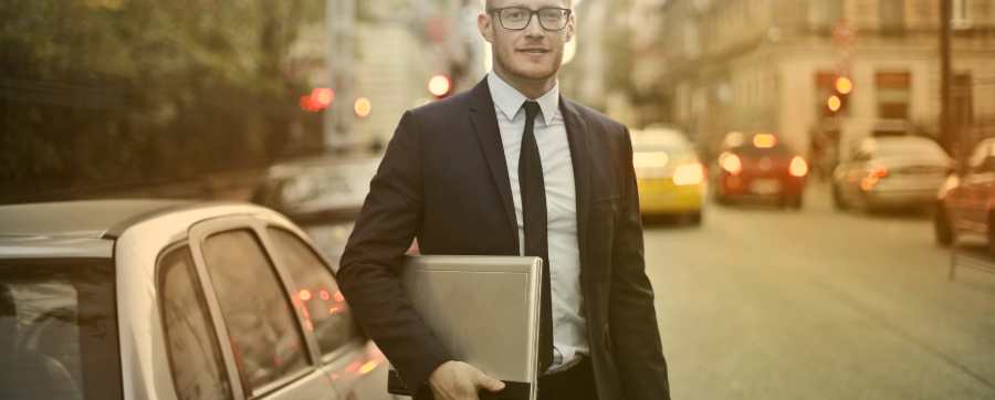 Man with laptop beside a car