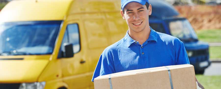 Delivery man with parcels in front of yellow van