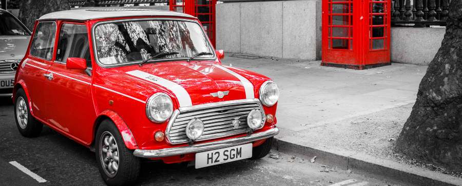 Image of a MINI parked by the side of a road in the UK with a telephone box