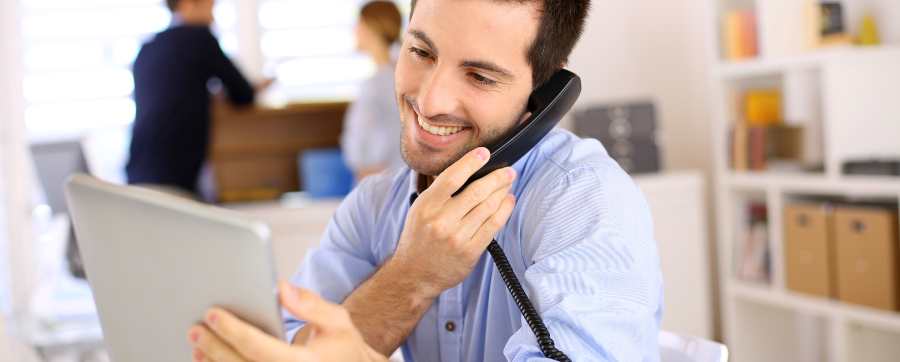 Man taking a phonecall and looking at a tablet for answers