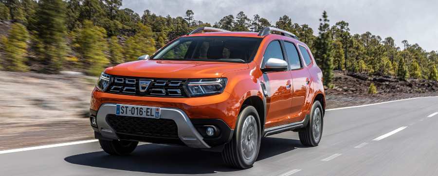 Orange Dacia sandero driving down a road in the sun