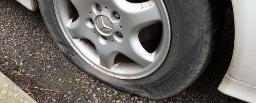 Flat tyre of a car on gravel pavement