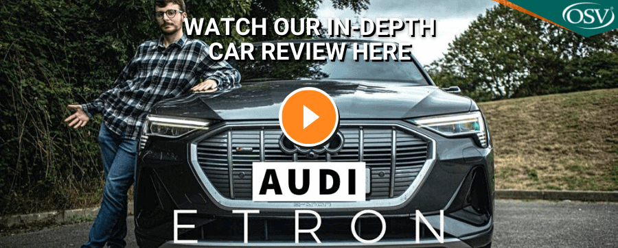 Audi E-Tron Video Thumbnail. Presenter standing leaning on car with play button in orange.