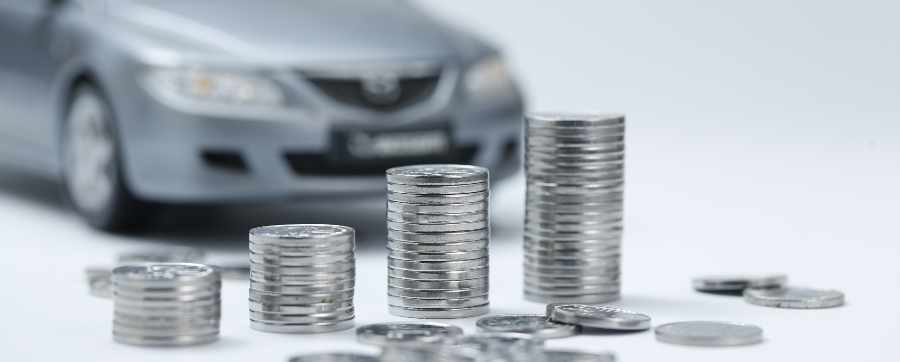 A blurry car behind a pile of silver coins - capital allowances on electric cars