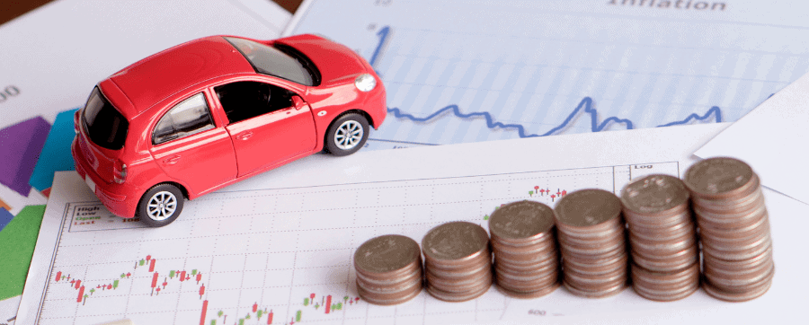 Small car model on paperwork and pile of coins